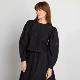 Blusa corta negra con bordado floral, mangas largas abullonadas y cuello redondo.