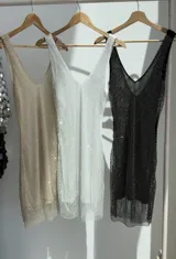 Vestido corto de fiesta con escote en V, confeccionado en tela de strass tornasolado y forro interior de tul alicrado a tono.