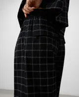 Pantalón de mujer color negro con estampado de cuadros blancos, corte barrel fit, cintura elástica en la espalda, bolsillos laterales y bolsillos de vivo con solapa en la espalda.