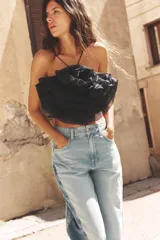 Top negro de organza con cuello halter, tirantes finos y detalle de maxi flor con volumen.