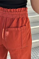 Pantalón de jean color beige, de corte ancho, recto y tiro alto. Tiene elástico y pinzas en la pretina.