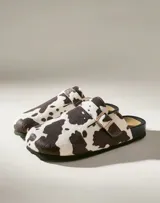 Zuecos con estampado de vaca en blanco y negro, con hebilla dorada ajustable.