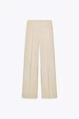 Pantalón color beige de lino, de tiro alto con cintura elástica, bolsillos laterales ocultos en costura y pernera ancha.