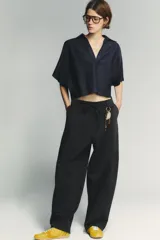 Zapatillas deportivas amarillas con detalles en negro y blanco. Presentan una combinación de materiales y texturas en el cuerpo, tirador en la lengüeta y cierre mediante cordones.