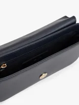 Cartera pequeña de poliuretano color azul marino con acabado liso. Presenta un diseño rectangular con solapa frontal que se cierra magnéticamente y lleva el monograma TH en metal dorado al frente. Incluye correa ajustable y extraíble para llevar al hombro o cruzada.