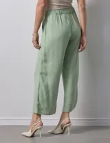 Pantalón de lino color crudo, de corte ancho y tiro alto, con bolsillos laterales y cintura elástica.