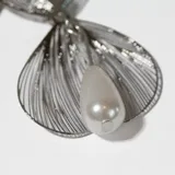 Par de caravanas colgantes plateadas con forma de flores y detalle de perla colgante.