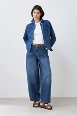 Campera clásica de jean color azul medio, con cuello clásico, cierre frontal con botones, bolsillos con solapa en el pecho y mangas largas con puños abotonados.
