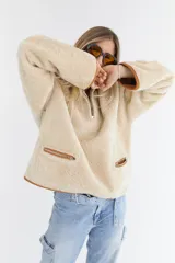 Buzo reversible de cuero genuino color beige, con cierre frontal parcial y bolsillos laterales con cremallera.