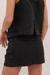 Chaleco negro de denim con proceso de encuerado, tres botones y dos bolsillos grandes laterales.