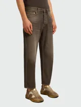 Jeans de hombre de corte recto, tiro medio, color marrón oscuro o negro lavado con efecto piedra. Presentan costuras en hilo amarillo y acabado ligeramente recortado en el tobillo.