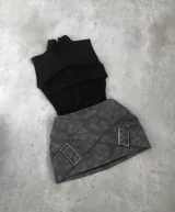 Minifalda gris con cinturón de cuero sintético con hebillas metálicas y ojalillos.