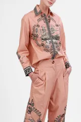 Camisa de popelina color rosa con estampado de paisajes italianos en blanco y negro. Tiene cuello clásico, mangas largas con puños abotonados y cierre frontal con botones.