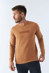 Remera color ocre de manga larga con cuello redondo y logo estampado en el pecho.