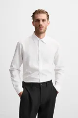 Camisa blanca de corte regular, cuello italiano, manga larga con puños abotonados y cierre frontal con botones.