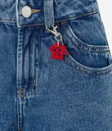 Short de jean de tiro alto, corte slim, con trabillas en la cintura, cierre tradicional, bolsillos y colgante de flor.