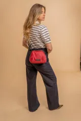 Bandolera pequeña de tela negra, con correa ancha ajustable y cierre superior.