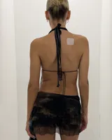 Conjunto de dos piezas, top estilo halter con escote profundo y falda corta con volados asimétricos. Ambas prendas son de tela transparente con estampado abstracto en tonos marrones, negros y toques de azul claro.