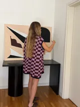 Vestido corto tejido en jacquard de algodón, con estampado a cuadros en tonos lila y borgoña, cuello redondo y cierre frontal con botones.