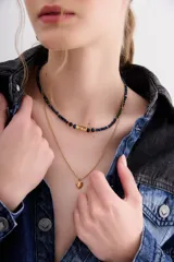 Collar doble con una cadena de piedras facetadas azules y verdes, y una cadena dorada de bolitas con un dije de corazón dorado.