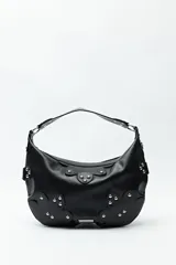 Cartera marrón de cuero sintético con forma de media luna, asa corta y apliques de tachas metálicas plateadas.