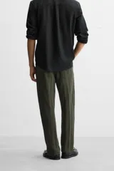 Pantalón verde oscuro con textura de rayas verticales, corte relaxed fit, cintura elástica ajustable con cordón, bolsillos delanteros y bolsillo trasero de parche.