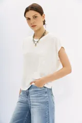 Remera de lino color crudo, de calce relajado con bordados de lurex y tachas en los hombros.