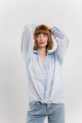Camisa color crema de manga larga con cuello camisero y detalles de encaje en el escote. Se ata en la parte delantera.