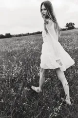 Vestido corto blanco con cuello mao de volados, mangas globo largas con puños fruncidos y falda escalonada con inserciones de encaje en escalera.