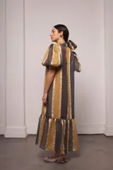 Vestido largo y amplio con cuello alto y estampado a rayas verticales en tonos dorado y gris. Incluye viso liso al tono.