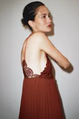 Vestido midi color ladrillo con tirantes finos, escote en pico y detalle de encaje en el busto. Tejido plisado y bajo asimétrico.