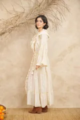 Vestido largo color crema con bordados florales en tonos pastel, escote en V con volados, mangas largas acampanadas y abertura frontal. Incluye lazo ajustable en la cintura.