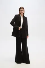 Blazer negro de corte holgado, con cuello solapa, cierre con doble botón y bolsillos laterales con solapa.