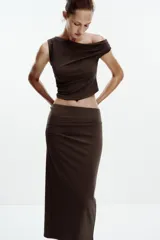 Falda midi color crema, de tiro alto con cintura elástica y detalle de pliegues laterales.
