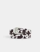 Cinturón de cuero sintético con estampado de vaca y hebilla metálica plateada.