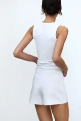 Falda pantalón corta negra de tiro medio con corte asimétrico.