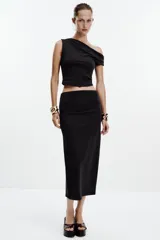 Falda midi color crema, de tiro alto con cintura elástica y detalle de pliegues laterales.