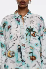 Vestido camisero corto de corte oversize, color blanco con bordado floral. Tiene cierre con botonadura frontal, escote camisero, manga larga con forma suave y puño, y bolsillo plastrón en el pecho.