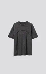 Remera de cuello redondo, calce oversize, color gris oscuro con efecto batik artesanal (acid wash). Presenta un corte curvo en la parte superior del pecho que simula un recorte.