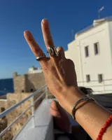 Anillo de diseño orgánico y macizo, realizado artesanalmente en bronce. Presenta una estructura abierta con dos piezas de forma irregular y textura rugosa.