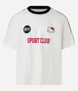Remera blanca de corte boxy con cuello redondo y detalles en negro. Estampado frontal con logo de Hello Kitty y texto "Sport Club".