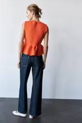 Top tejido de punto color naranja, de cuello redondo y sin mangas. Tiene corte ajustado en el torso y peplum en la cintura.