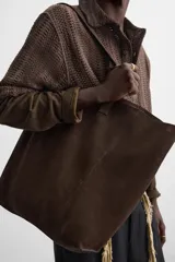 Bolso tipo shopper color marrón claro, fabricado en piel serraje. Cuenta con dos asas de mano y un bolsillo interior con cierre de cremallera.