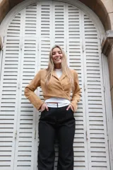 Chaqueta corta color camel con cuello solapa, corte cruzado y cierre con botón.