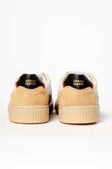 Zapatillas deportivas color beige con detalles en gris, blanco, negro y rojo.