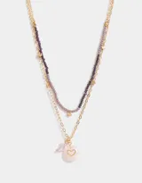 Collar corto multicadena con mostacillas lilas y dije de corazón místico dorado.
