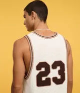 Musculosa de punto color crema con cuello redondo y bies contrastante en marrón. Presenta el número 23 estampado en el frente y un pequeño logo con una estrella.