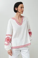 Blusa blanca de lino con bordados rojos en cuello, mangas y ruedo, de corte holgado y manga larga.