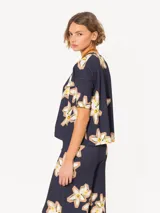 Remera azul marino con estampado de flores blancas y amarillas, de corte holgado, cuello redondo y mangas cortas.