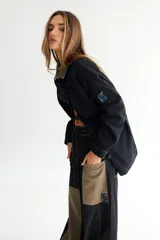Campera de jean azul con corte oversize, cuello de pana color borgoña, cierre con botones metálicos y cinturón de lazo.